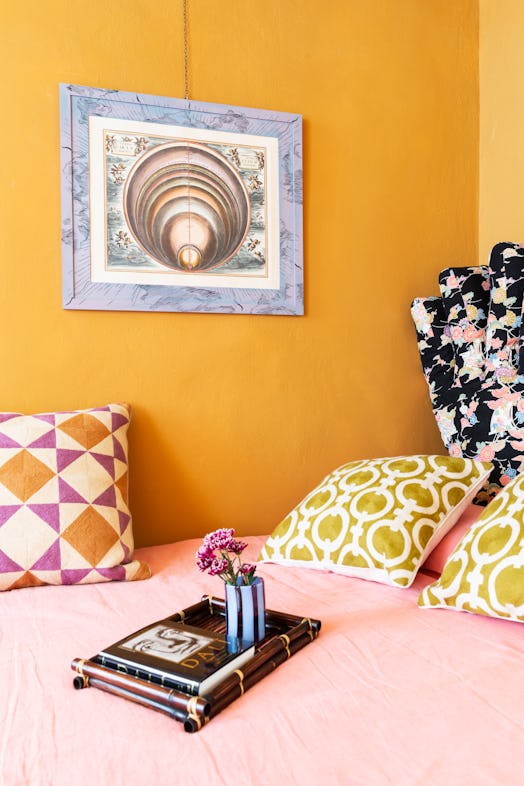 a bed with a framed print above it and colorful pillows