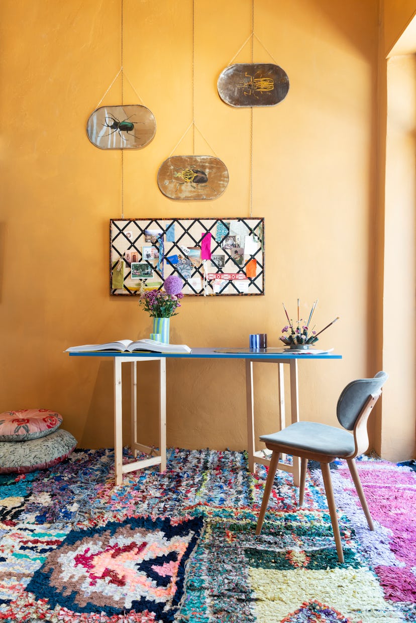 Over a patchwork of vintage rugs, a custom table and chair hold an array of Taschen books and cups b...