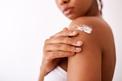 Woman apply cream to shoulder