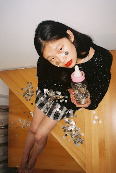 Young woman playing with coins and a baby bottle to show how old she is mentally, according to her z...