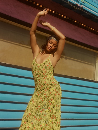 'Zola' star Taylour Paige poses outside with her arms in the air wearing a yellow Bottega Veneta dre...