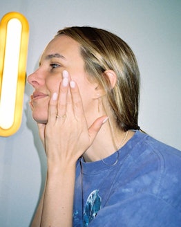 Tracy Dubb washes her face in front of a modern light fixture