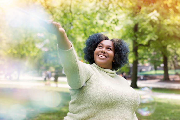 Young woman playing with bubbles on a Saturday before posting a fun picture with a weekend caption o...