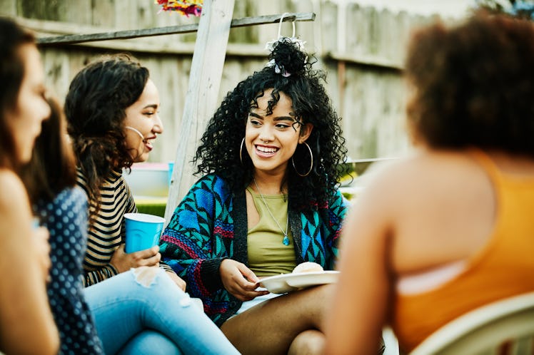 Young woman meeting friends after a long time at her college reunion, getting ready to post picture ...