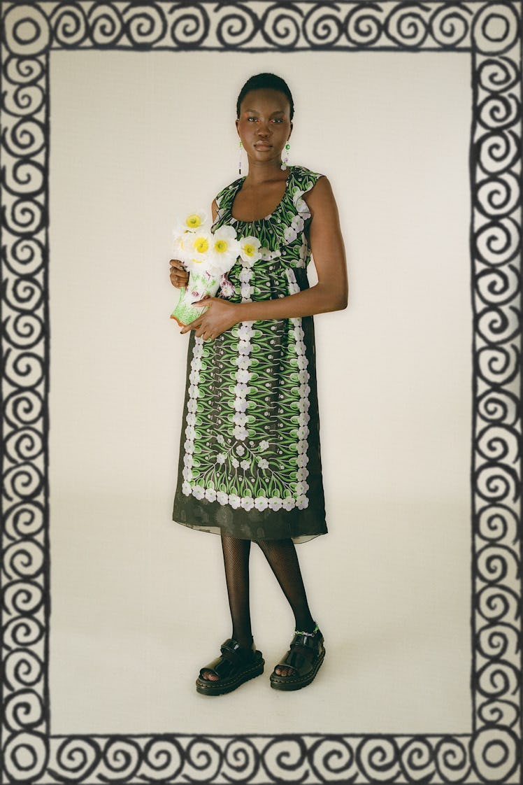 A woman posing while wearing a green, black, and white dress