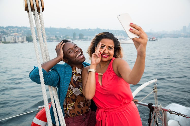 Young couple taking a funny selfie on a boat before posting it on Instagram with boat puns, sailing ...