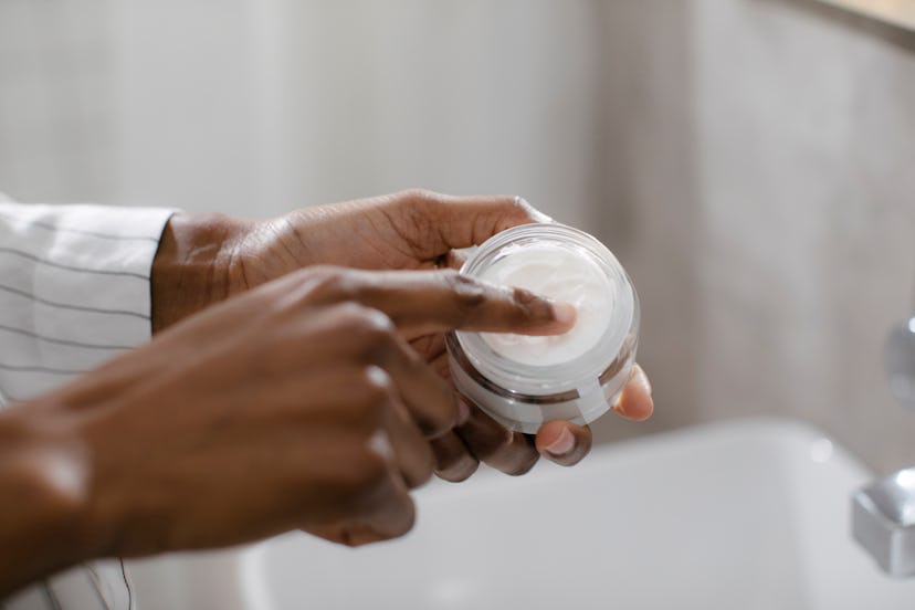 Woman applying cream with urea from a jar