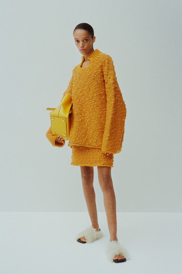 A woman posing while wearing an orange Proenza Schouler blouse and skirt combination