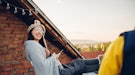 Young woman laughing on a rooftop, thinking of a funny comment to post on her partner's Instagram.