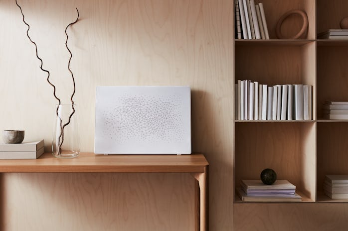 a white picture frame leans against a light-colored wood wall