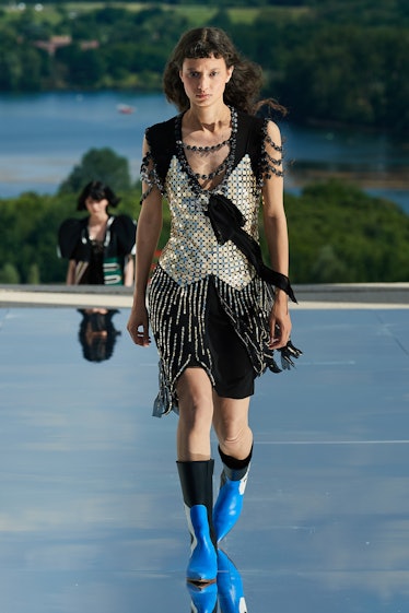 A female model walking while wearing a black and silver Louis Vuitton dress