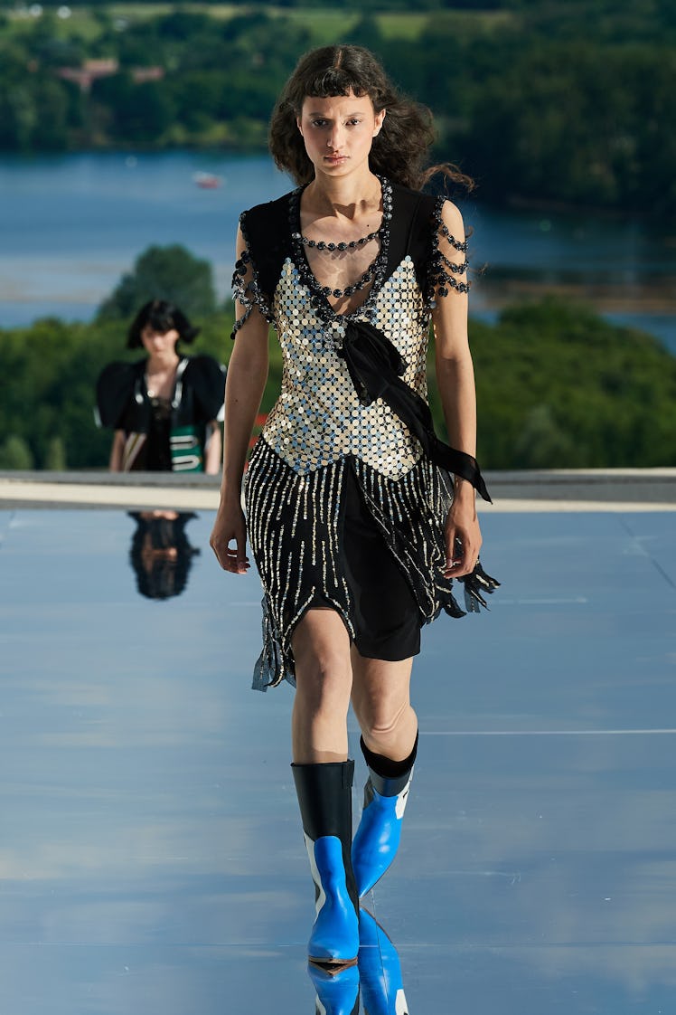 A female model walking while wearing a black and silver Louis Vuitton dress