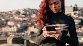 Young woman on a rooftop, texting her WhatsApp family group chat with a fun name.