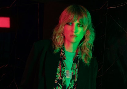 Singer Ladyhawke posing in a dark outfit and a dark background. 