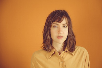 Close-up of Laura Stevenson in an orange shirt, with an orange backdrop.