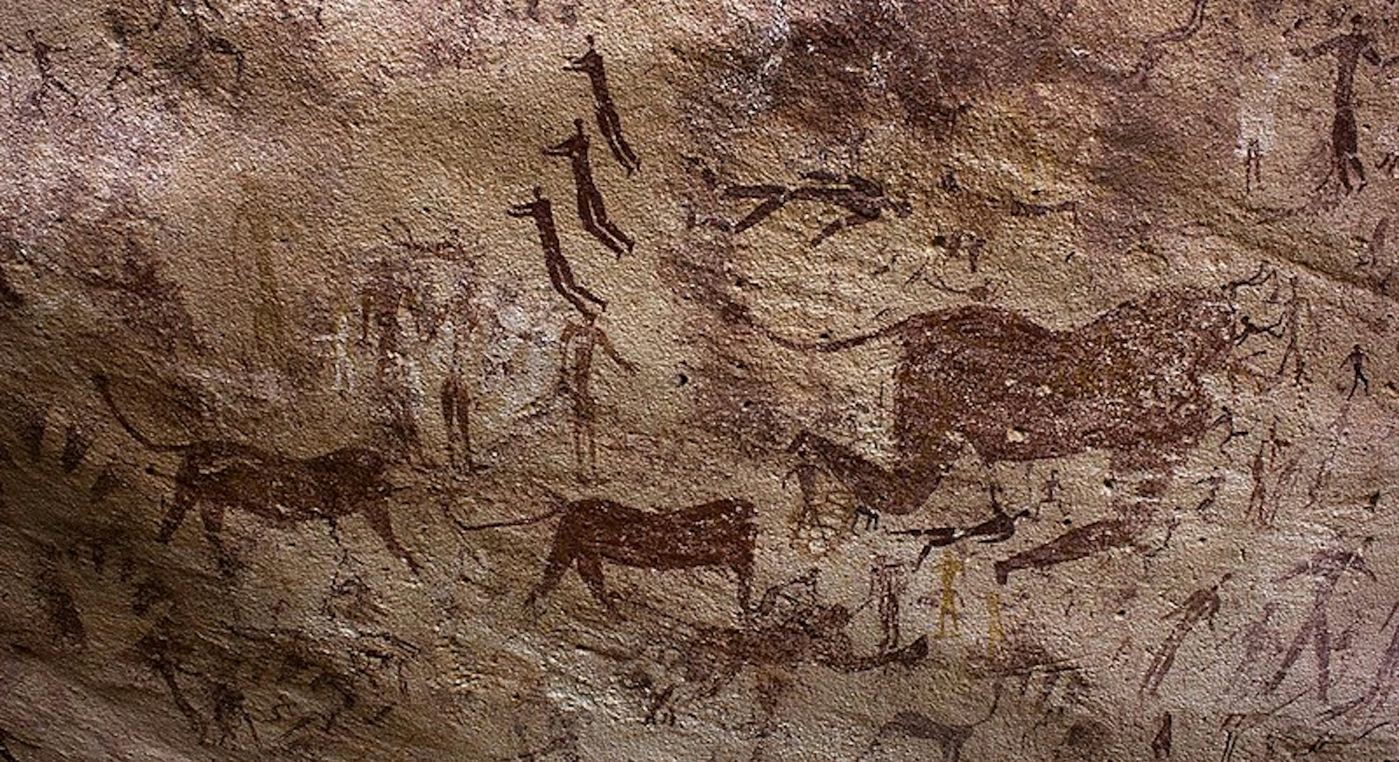 Paintings of human figures and animals on a brown cave wall