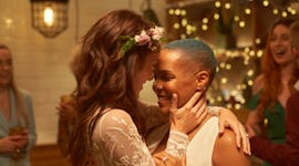 Young brides smiling & gazing into each other's eyes on their wedding day, using a funny wedding has...