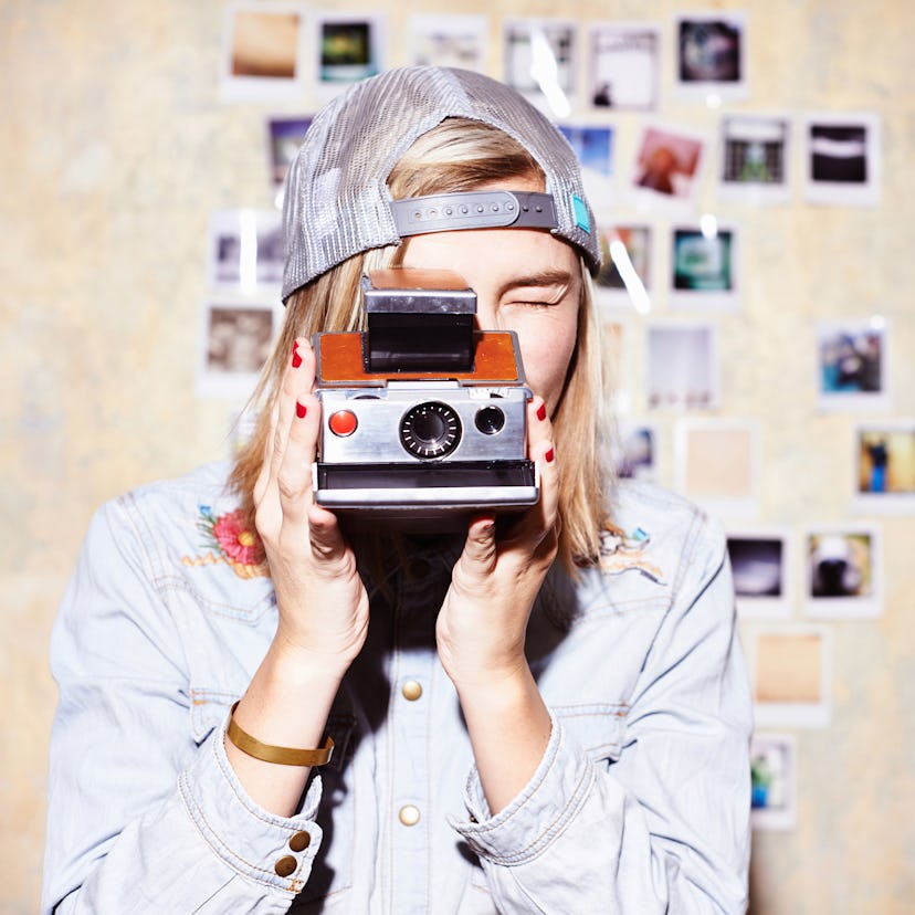 Young woman taking a picture with a Polaroid camera, in need of Instagram captions, quotes.