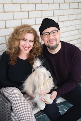 Lydia Liebman, her partner and their dog in their laps on a couch outside of their house
