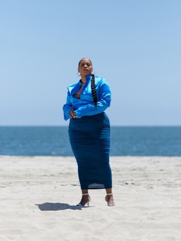 Danielle Williams Eke posing in a light blue shirt and denim long skirt on a beach