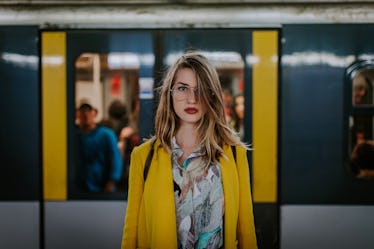 Young woman taking a picture in a subway station before posting a picture on Instagram with a train ...