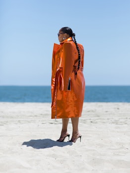 Danielle Williams Eke posing in an orange coat on a beach