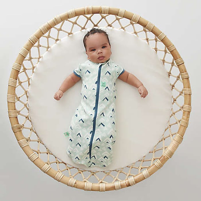 baby in a swaddle lying in crib looking up at camera