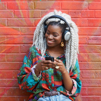 Happy young woman holding her phone, having the best week of June 7, 2021, per her zodiac sign.