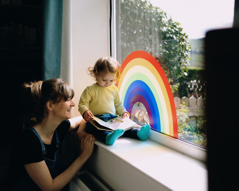 woman and child reading a children's book on windowsill with rainbow painting, best lgbtq children's...