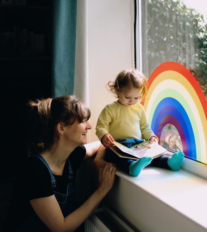 woman and child reading a children's book on windowsill with rainbow painting, best lgbtq children's...