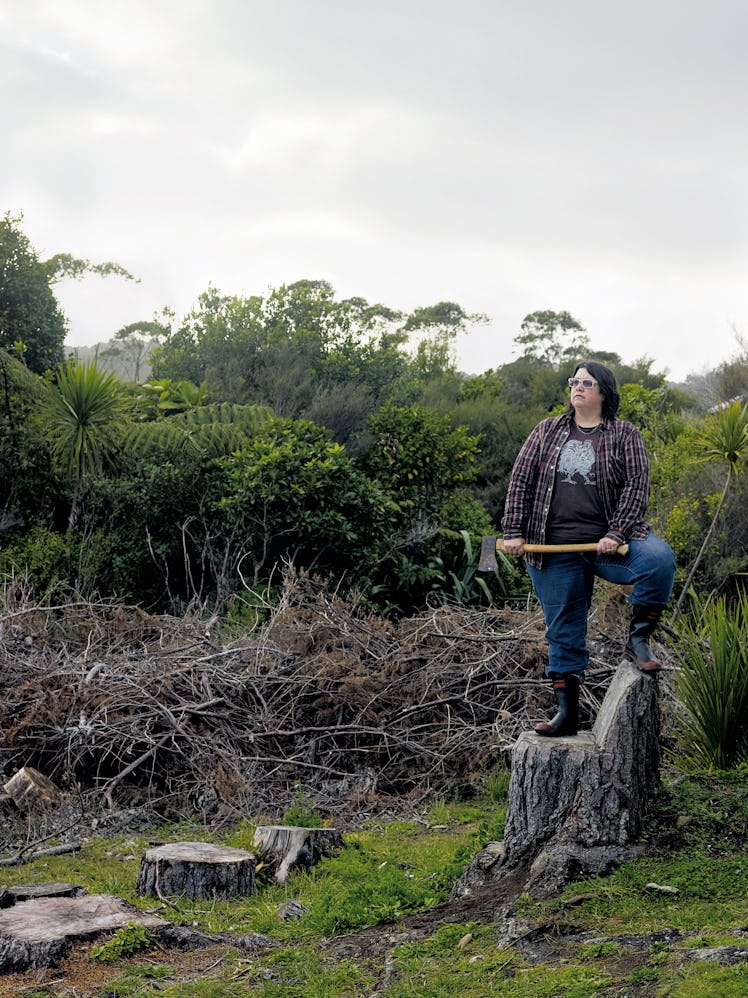 A self-portrait by Catherine Opie standing on a wood stump, and holding an axe