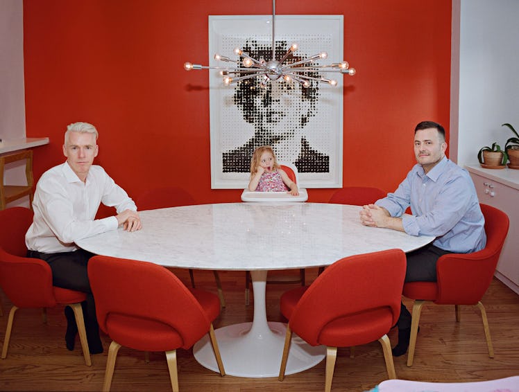 Two man, Patrick and John sitting at oval dinning table with their daughter Mila.