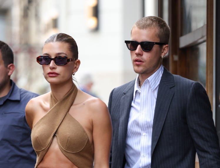 Hailey Bieber in a camel cut-out dress, and Justin Bieber in a grey suit and a blue shirt when they ...
