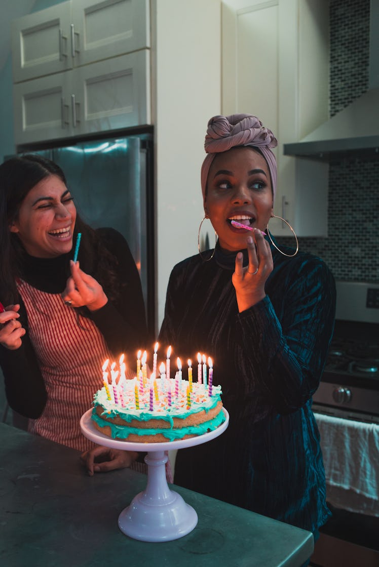 Young woman licking the candle on her birthday cake before posting a happy birthday caption on Insta...