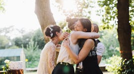 Friends laughing & hugging at a wedding before posting on social media with Instagram captions for a...