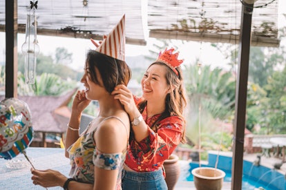 Young friend helping put a party hat on her friend's head before posting a happy birthday caption on...