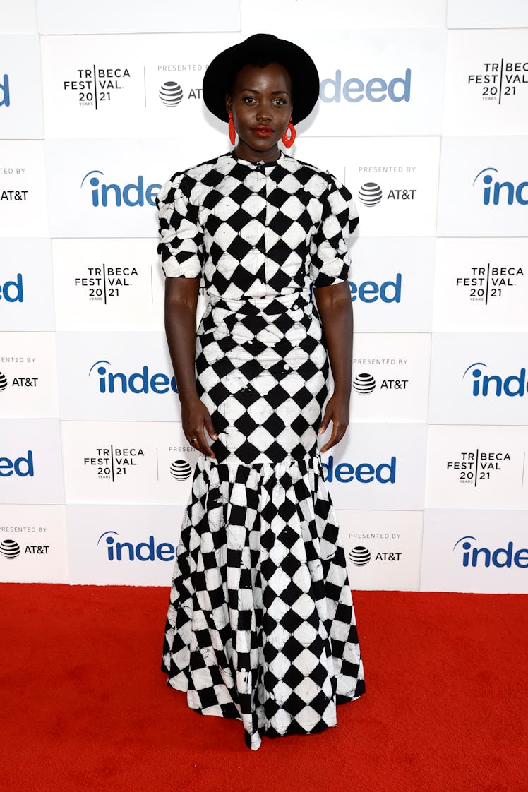 Lupita Nyong'o in a checkered dress and a black fedora hat 