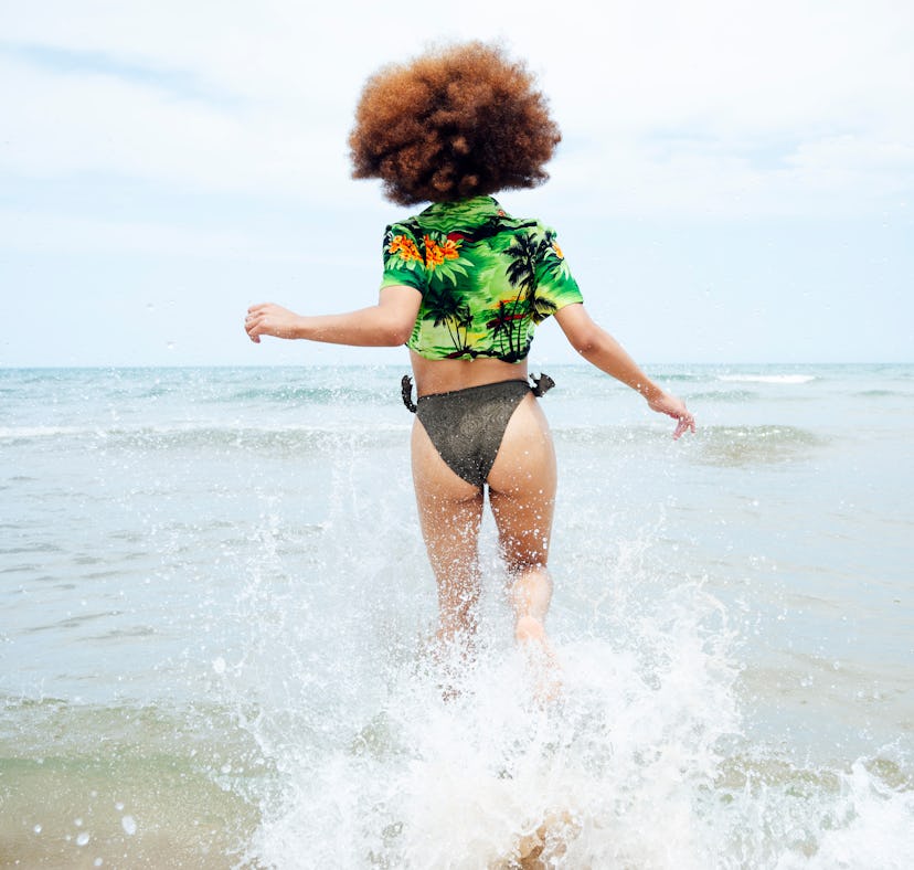 Young woman running into the ocean, in need of wave quotes for Instagram.