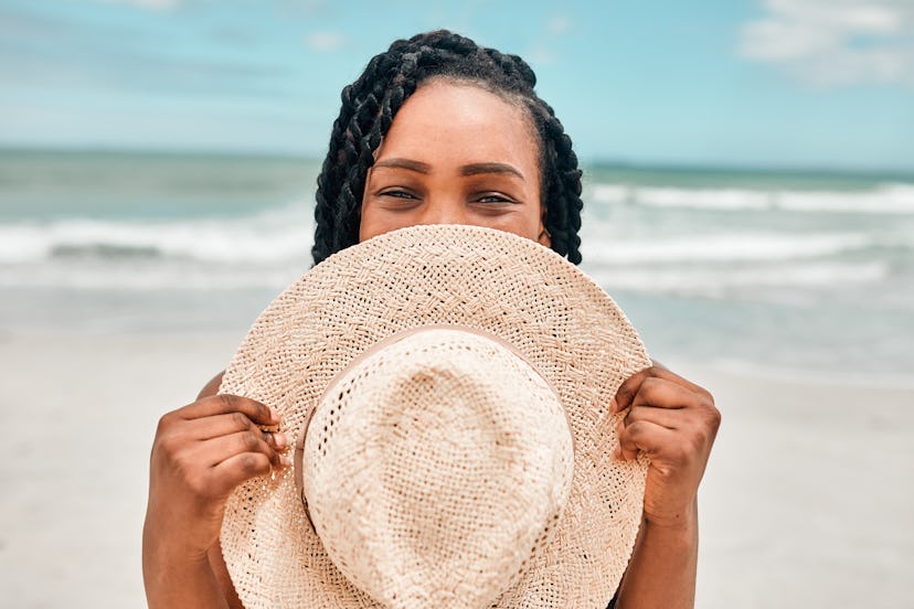 Woman on beach holding a straw hat