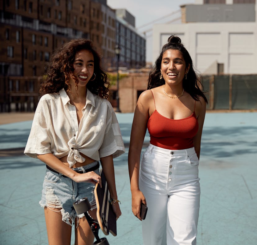2 young women laughing and walking before posting a pic with the best hashtags for Instagram Stories...