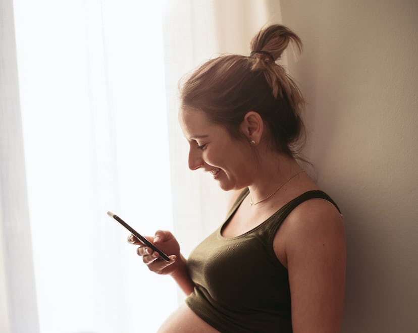 Pregnant woman smiling at cell phone