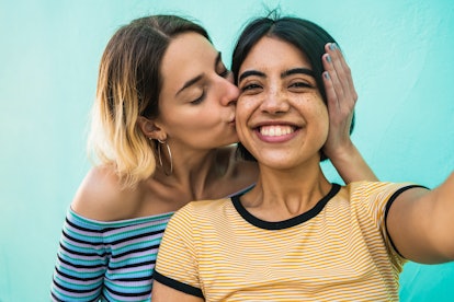 Young Libra woman kissing her Libra girlfriend on the cheek.