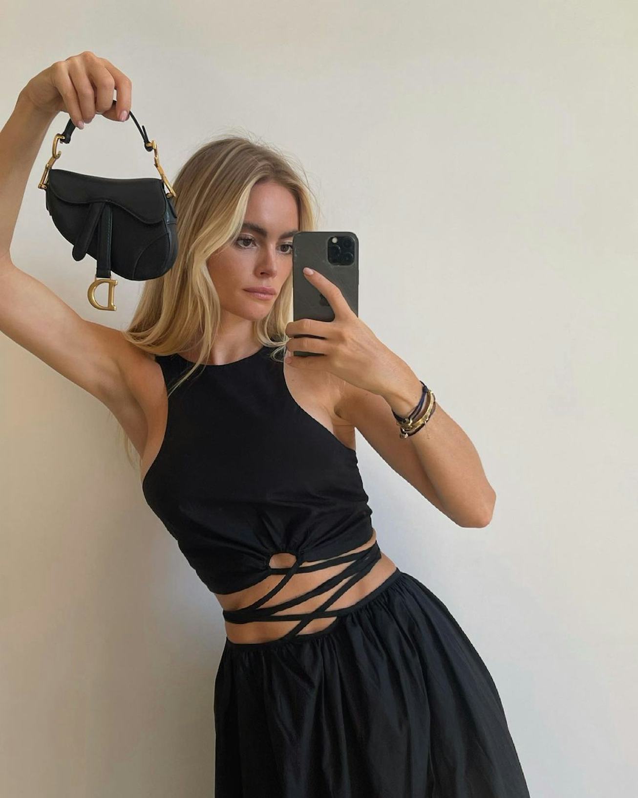 Claire Rose holding a tiny Dior Saddle Bag.