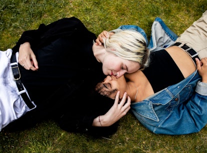Young couple laying in the grass kissing, showing why Cancers are so good in bed.