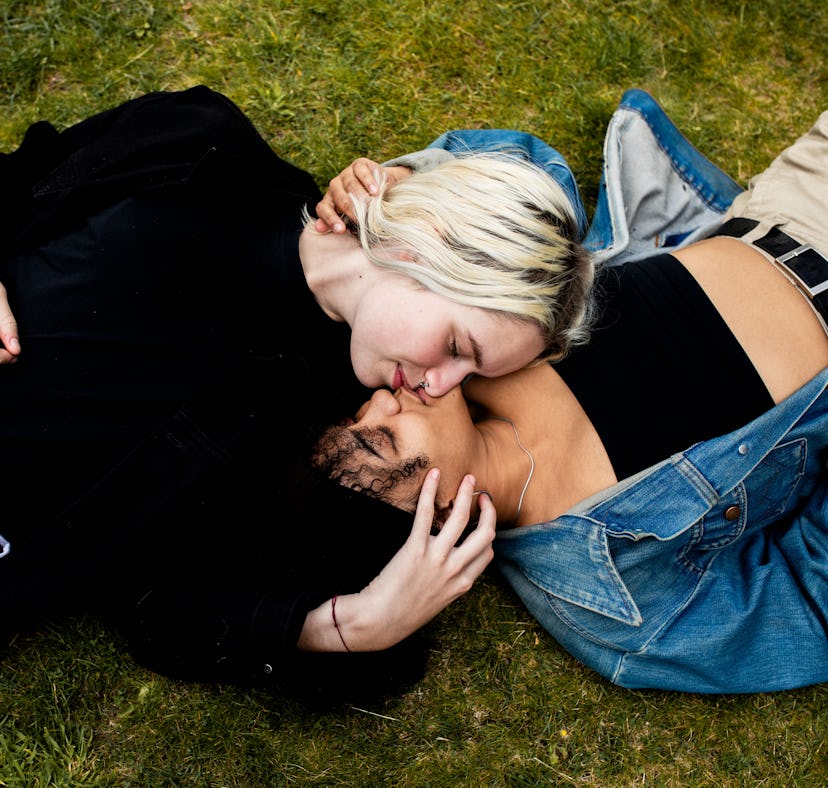 Young couple laying in the grass kissing, showing why Cancers are so good in bed.