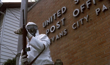 a man in a hazmat suit with a gun standing in front of the us post office in the movie The Crazies