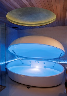 A flotation therapy chamber opened with a blue light coming out 
