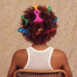 The back of a woman with curly natural hair an various afro picks placed in her hair