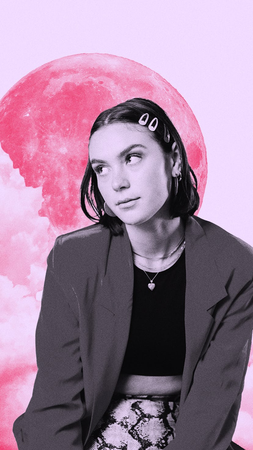 Young woman with clips in her hair in front of a pink moon while reading her July 2021 monthly horos...