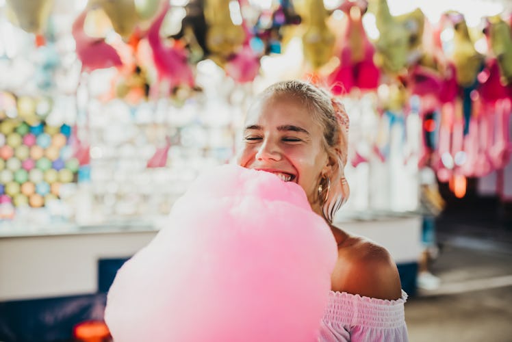 Young woman eating cotton candy before posting an Instagram with a sweet candy pun.